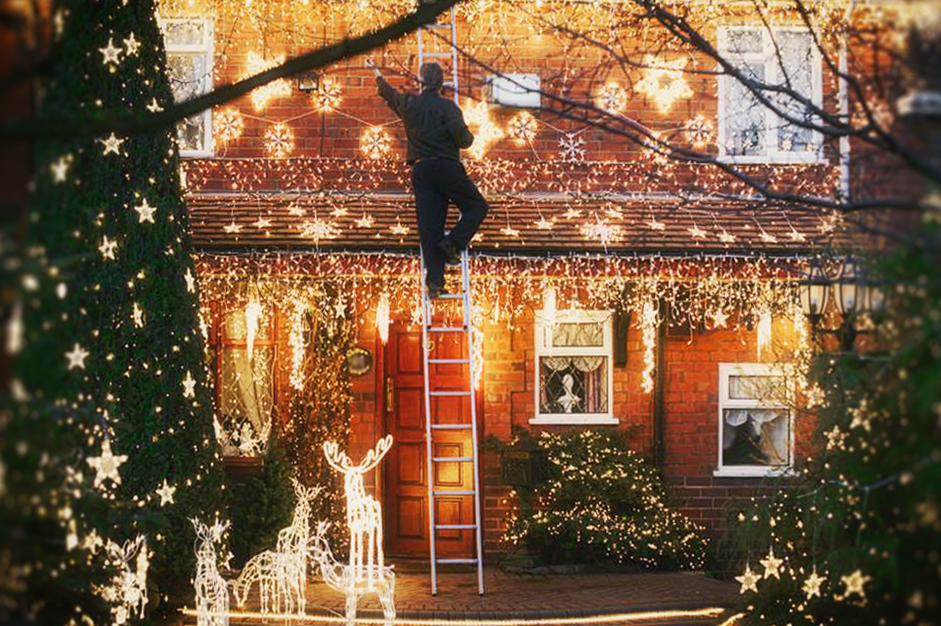 man-hanging-christmas-decorations-on-roof